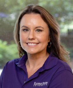Kelsy Sproul, a woman with brown hair and a purple K-State polo, is shown in front of a nature backdrop.